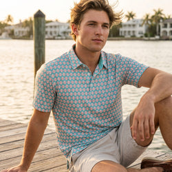 Person wearing a teal polo shirt with a baseball pattern on a pier.