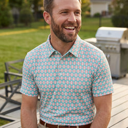 Man wearing a blue polo shirt with baseball pattern at an outdoor cookout.