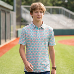 Person wearing a blue baseball polo shirt with baseball pattern on a field.