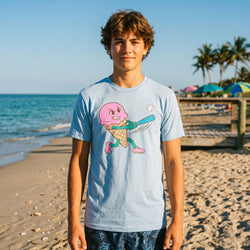 Person wearing a t-shirt with a colorful ice cream baseball graphic on a beach