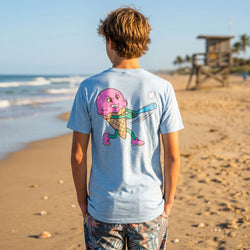 Person wearing a light blue t-shirt with a cartoon ice cream character on the beach