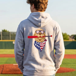 Person wearing a hoodie with a dog graphic on a baseball field