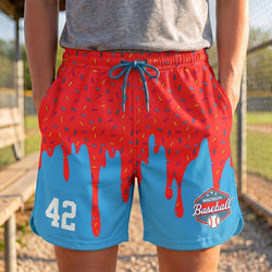 Person wearing red and blue shorts with a baseball design on a sports field.