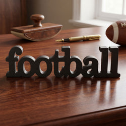 Wooden 'Football' sign on a wooden surface with a football and other items in the background.