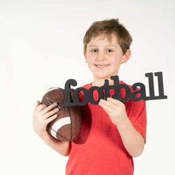 Child holding a football and black decorative wood with the word 'football' against a white background