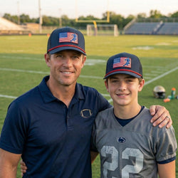 Man and young boy wearing American flag football hats on a sports field