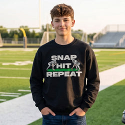 Person wearing a black sweatshirt with football-themed text on a football field