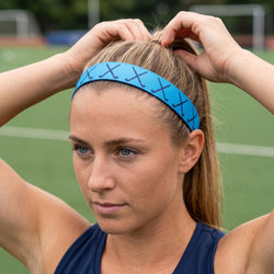 Woman adjusting a blue headband on a sports field