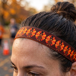 Person wearing a headband with a pattern of turkeys outdoors