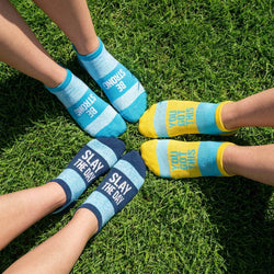 Three pairs of socks with motivational text on a grassy background