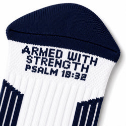 A close-up of a white and navy blue crew sock with the text 'ARMED WITH STRENGTH PSALM 18:32' knitted into the side.