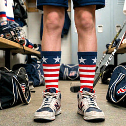 Person wearing American flag hockey socks in a sports locker room.