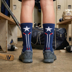 Person wearing blue hockey socks with star and stripe design in a locker room.