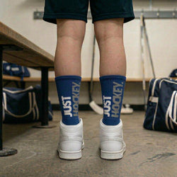 Person wearing blue socks with 'Just Hockey' text in a hockey locker room.