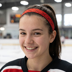 Woman wearing a red headband with black hockey stick patterns, standing in an indoor setting.