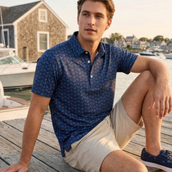 Teen wearing a hockey patterned polo shirt outdoors by a pier.