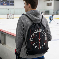 Person wearing a drawstring bag with 'I'd Rather Be Playing Hockey' text on an ice rink.