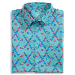 A folded short-sleeve button-up shirt in turquoise with an all-over hockey stick pattern in blue and red, shown on a plain white background.