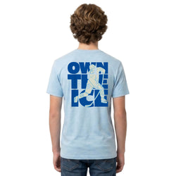 Person wearing a light blue t-shirt with a hockey graphic design on the back, standing against a white background.