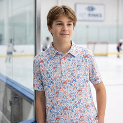 Person wearing a patriotic themed polo shirt with hockey pattern design at an indoor hockey rink.