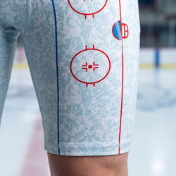 Close-up of a person wearing hockey shorts with red and blue graphics on a blurred background
