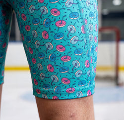 Teal hockey shorts with donut pattern worn by a person indoors.