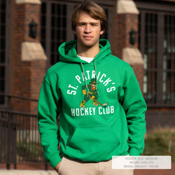 Person wearing a green 'St. Patrick's Hockey Club' hoodie in front of a brick building.