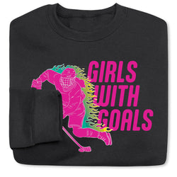 Black folded sweatshirt with a graphic of a hockey player and 'Girls with Goals' text on a white background