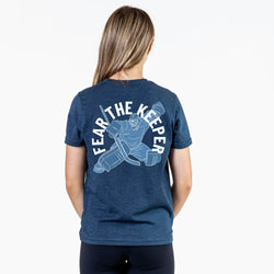 Girl wearing navy t-shirt with hockey goalie design and 'Fear the Keeper' text on a white background