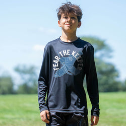 Child wearing a black long-sleeve shirt with 'Fear The Keeper' text and graphic outdoors.