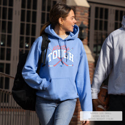 Person wearing a blue hoodie with text, walking outdoors.