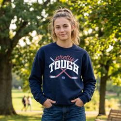 Person wearing a navy blue sweatshirt with 'pretty tough' text in a park setting