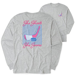 Gray long-sleeve shirt with hockey graphic and text 'She Shoots, She Scores' on a white background
