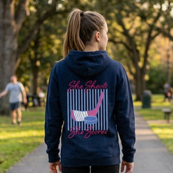 Person wearing a navy hoodie with a hockey girl-themed design in an outdoor setting
