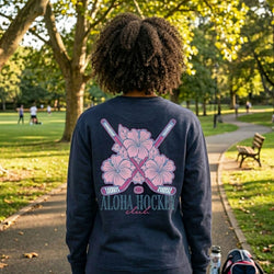 Person wearing a navy sweatshirt with pink floral and baseball bat design in a park.