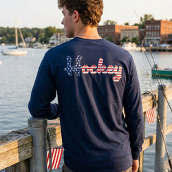 Person wearing a navy blue long-sleeve shirt with 'Hockey' printed on the back, standing on a dock by a body of water.