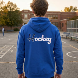 Person wearing a blue hoodie with 'Hockey' printed on the back in an outdoor setting.