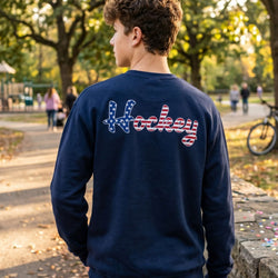 Person wearing a navy blue sweatshirt with 'Hockey' printed on the back in a park setting.