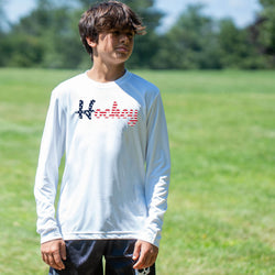Person wearing a white long sleeve tee with a patriotic hockey script design outdoors