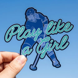 Sticker with hockey player and 'Play like a girl' text held against a blue background