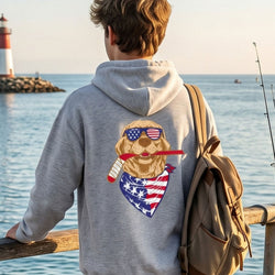 Person wearing a hoodie with a dog graphic by a lighthouse and ocean.