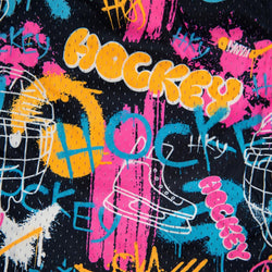 A close-up of a black fabric featuring a vibrant, graffiti-style hockey graphic print with the word 'HOCKEY' in yellow, pink, and blue paint splatters, along with skates and hockey sticks.