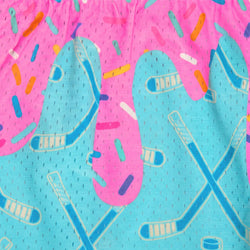 A close-up of a bright pink and turquoise patterned fabric featuring a dripping donut design with hockey sticks, hockey pucks, and colorful sprinkle accents.