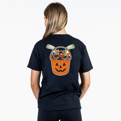 A woman viewed from the back wearing a dark navy T-shirt with a large Halloween-themed graphic on the back. The graphic shows a jack-o'-lantern bucket filled with candy and hockey pucks.