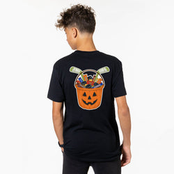 A young man viewed from behind wearing a black t-shirt with a large Halloween graphic on the back. The graphic features a jack-o'-lantern bucket filled with candy and hockey pucks.