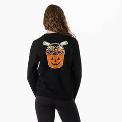 A woman shown from the back wearing a black sweatshirt with a large Halloween-themed graphic on the back. The graphic features a jack-o'-lantern bucket filled with candy and hockey pucks.