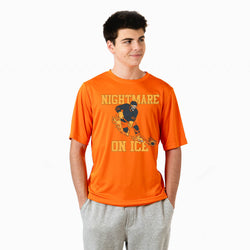 A young man wearing a bright orange t-shirt with a graphic of a hockey player and the text 'NIGHTMARE ON ICE' in yellow, paired with gray sweatpants, against a plain white background.