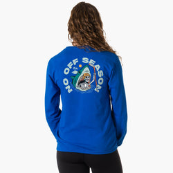 A woman viewed from behind wearing a bright blue long-sleeve sweatshirt with a large graphic on the back. The graphic features a shark with a skeleton holding a hockey stick coming out of its mouth with the words 'NO OFF SEASON' in white around it, set against a light gray studio background.