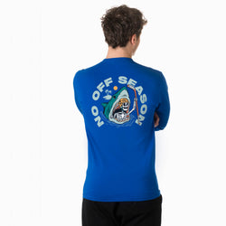 A man viewed from behind wearing a royal blue long-sleeve t-shirt with a large graphic on the back. The graphic features a skeleton coming out of a shark's mouth holding a hockey stick, surrounded by the text 'NO OFF SEASON' in light blue.