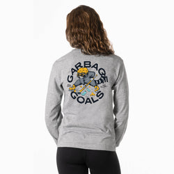 A girl viewed from behind wearing a heather gray long-sleeve shirt with a large back graphic that reads 'GARBAGE GOALS' around a cartoon raccoon hockey character. She is also wearing black leggings against a plain white studio background.